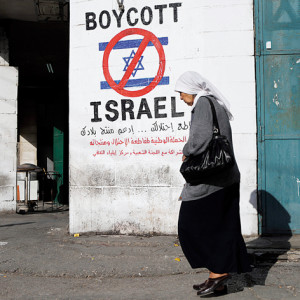 epa04502157 A picture made available on 24 November 2014 shows a Palestinian woman passing a graffiti sign calling to boycott Israeli, seen in the West Bank town of Bethlehem, 20 November 2014. The Middle East Studies Association that has over 2,700 members and is considered one of the leading organisations in Middle East studies, is expected to vote on 24 November 2014 for its member stop support an academic boycott on Israeli academic institutions. EPA/JIM HOLLANDER